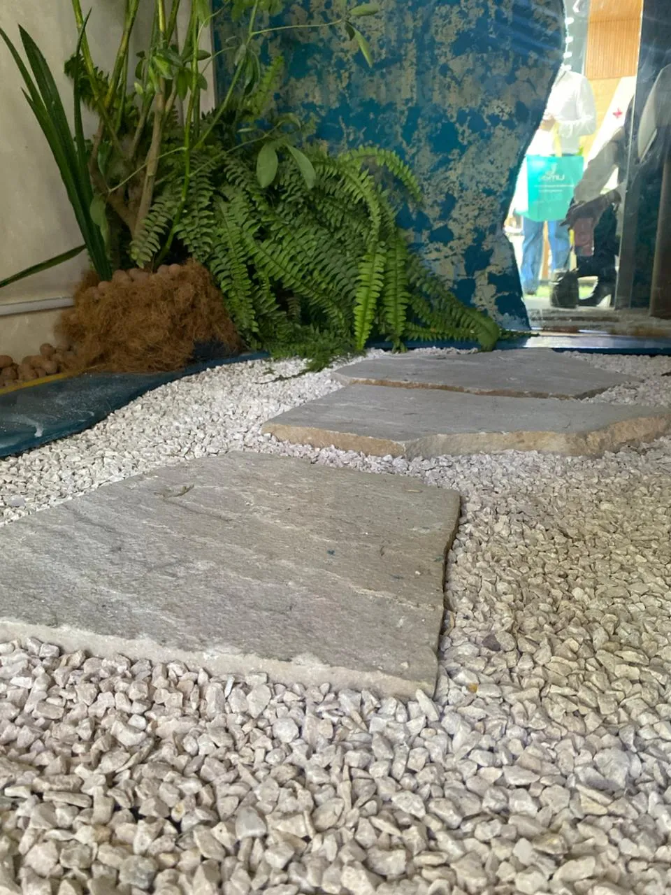 Camino de lajas con granalla blanca y helechos en stand ExpoDeco