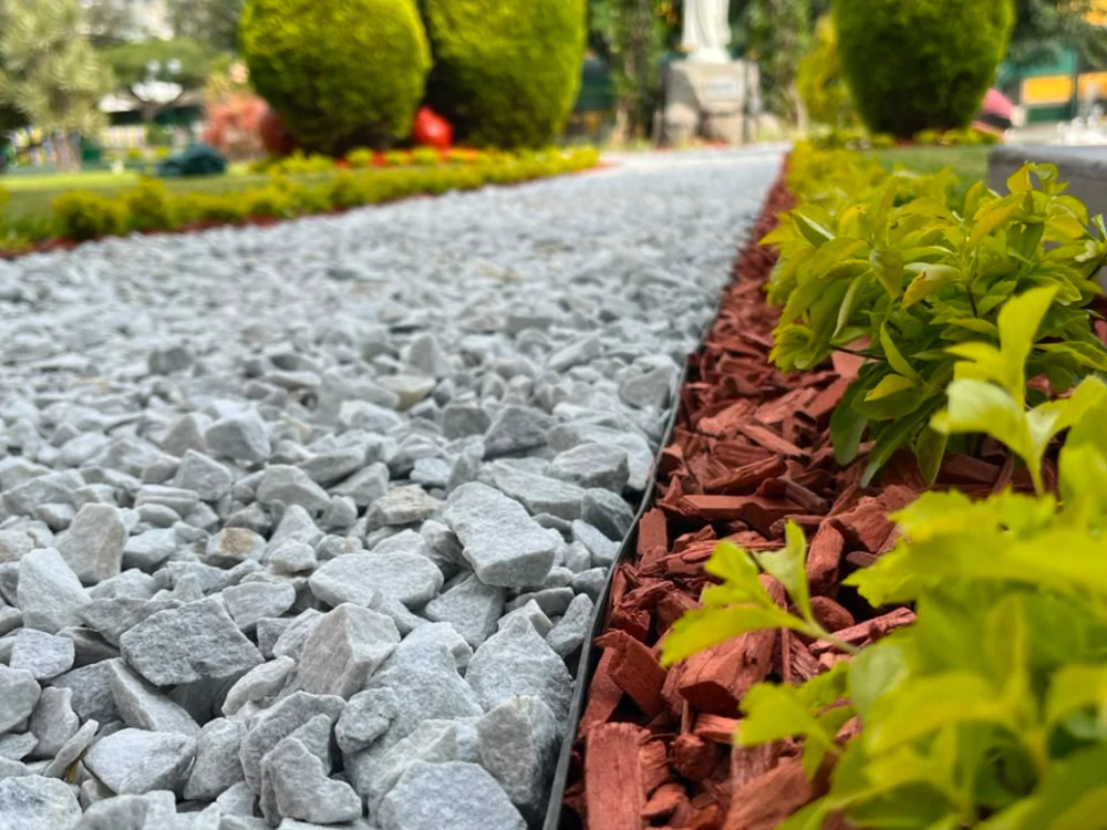 Separador de jardín negro delimitando granalla blanca y mulch rojo en un proyecto de paisajismo Samay