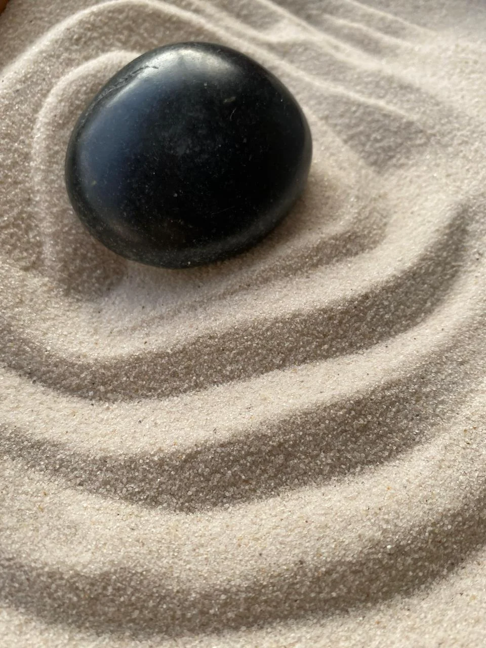 Piedra zen negra sobre arena sílice rastrillada